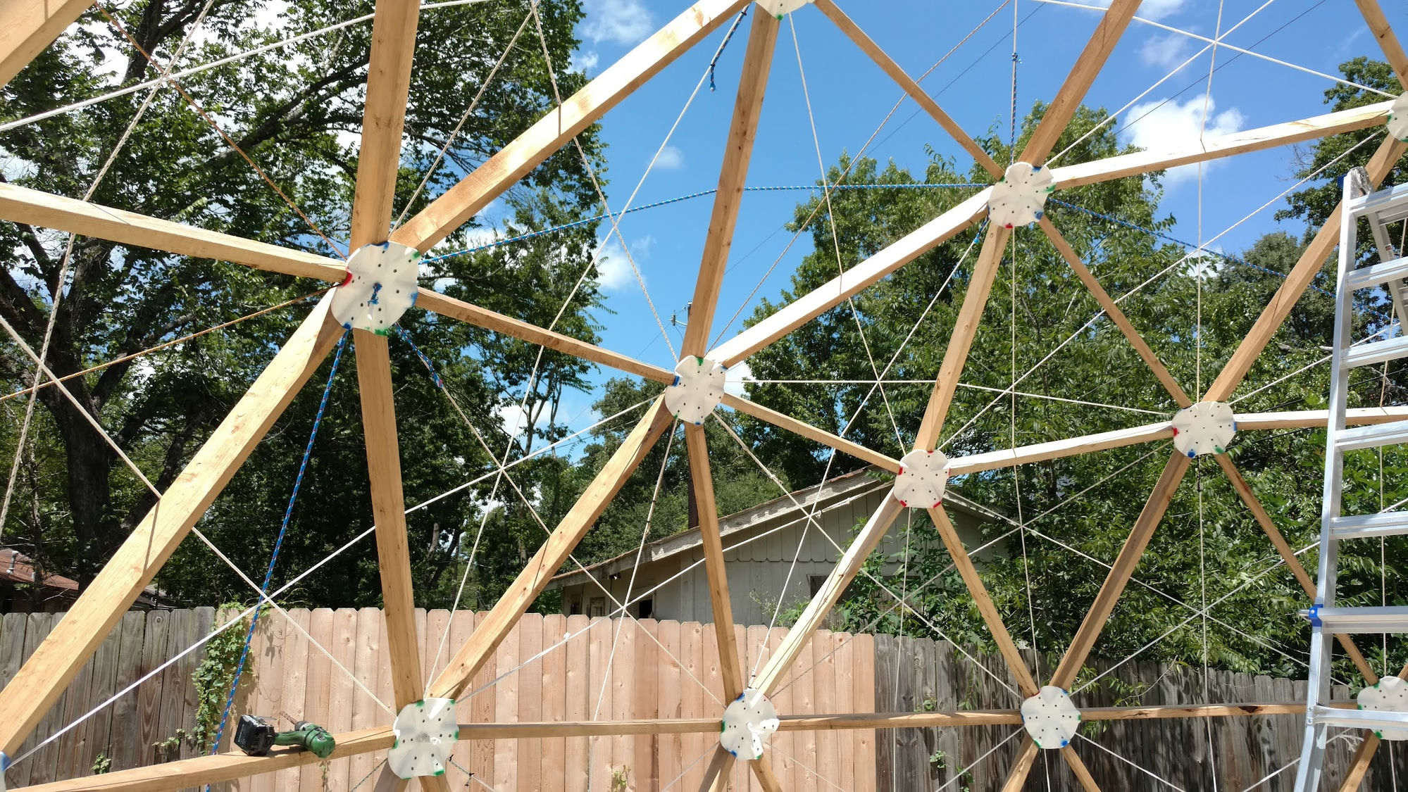 Inside the proof dome frame: white scalloped PVC hub discs at every joint, color-coded strut ends visible